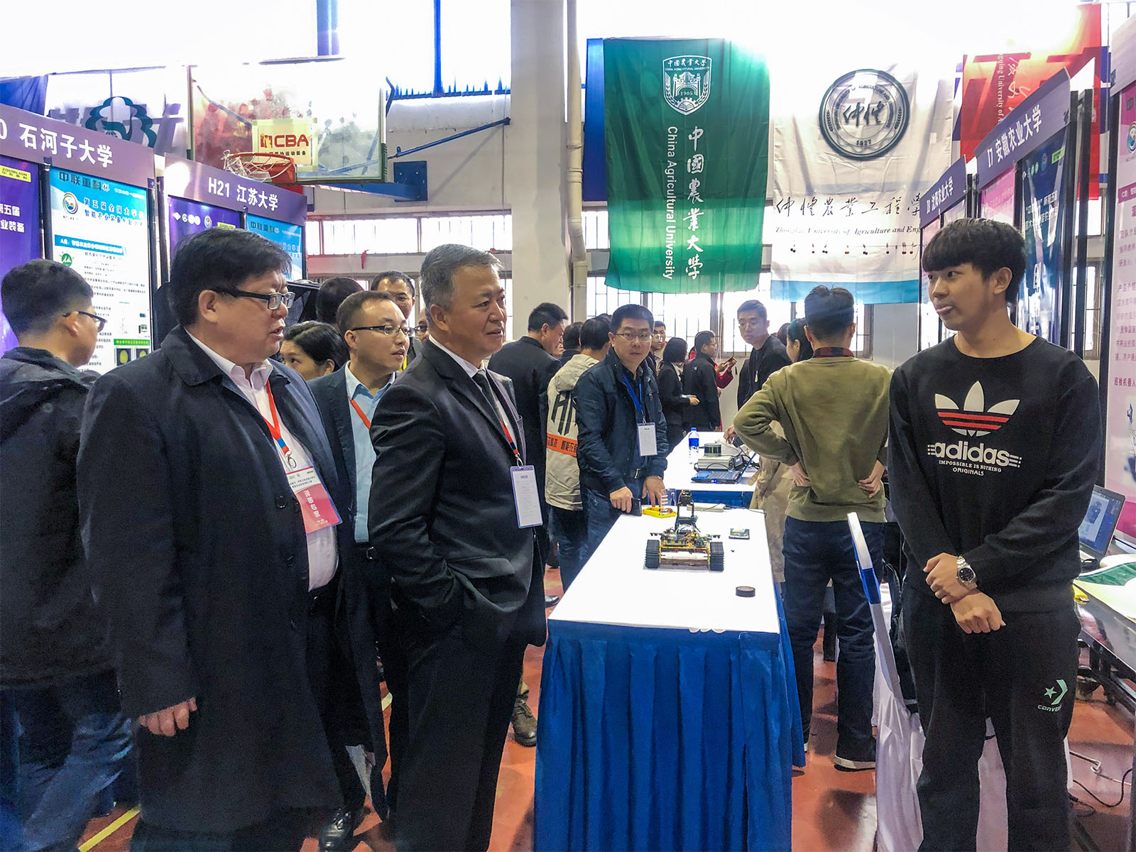 中国农业机械化科学研究院党委书记、院长王博（中），中国农业机械学会秘书长张显胜（左一）对李慧莱同学的作品很感兴趣，并鼓励同学们将来积极投身国家农业工程事业